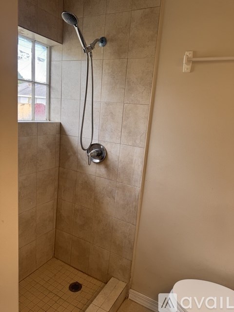 A tiled shower with a glass door and a drain in the floor.