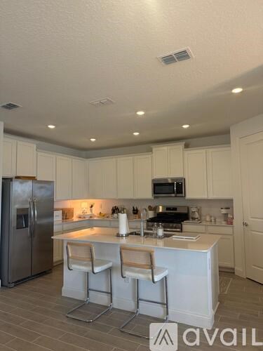 A kitchen with white cabinets and a stainless steel refrigerator.