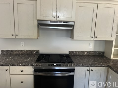 A kitchen with a stove top oven and cabinets.