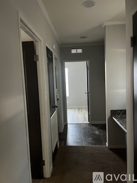 A hallway with a carpeted floor and a white door at the end.