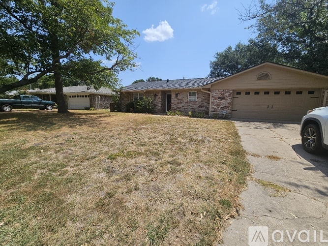A house with a garage and a tree in front of it.