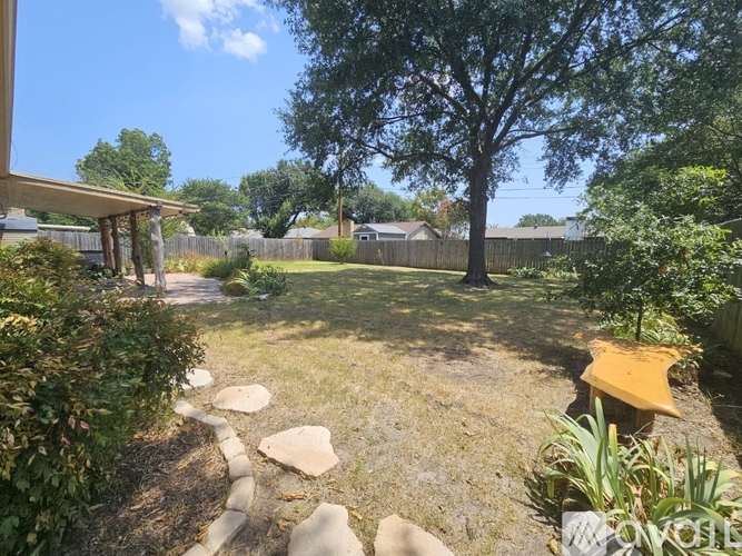 A backyard with a stone pathway and a yellow chair.