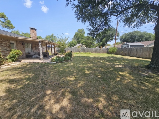 A backyard with a fence and a house in the background.