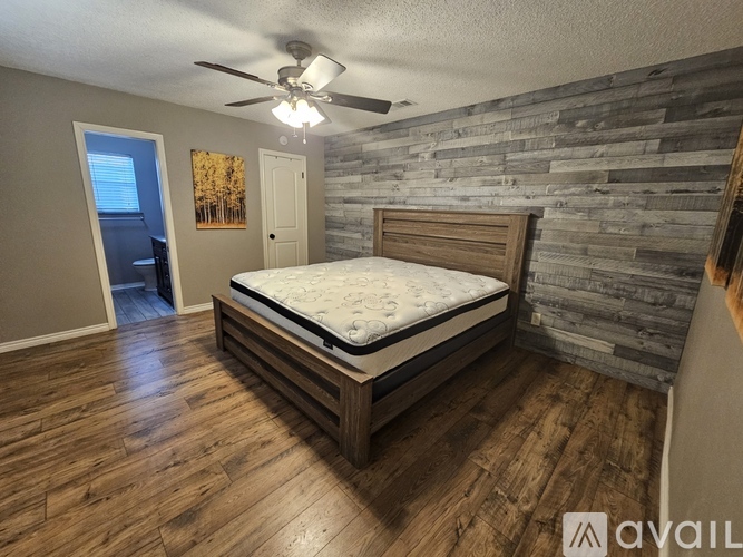 A bedroom with a bed, wooden floors, and a stone wall.