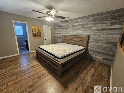 A bedroom with a bed, wooden floors, and a stone wall.