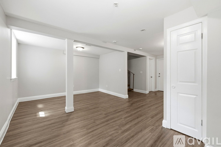 A spacious room with wooden flooring and white walls.