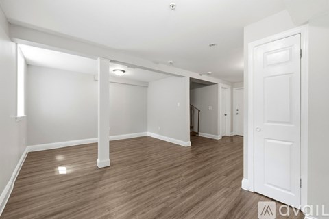A spacious room with wooden flooring and white walls.