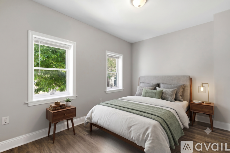 A bedroom with a large bed and two windows.