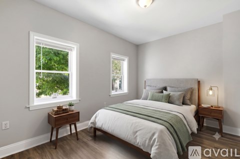 A bedroom with a large bed and two windows.