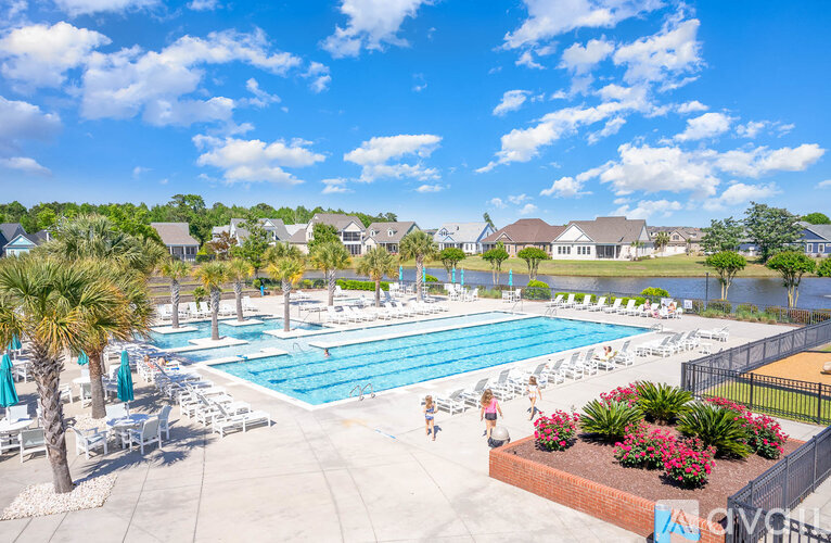 A pool surrounded by palm trees and a fence with the letters "ACV" on it.