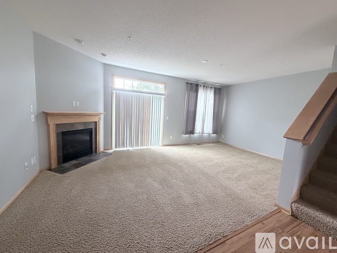 A living room with a carpeted floor and a fireplace.