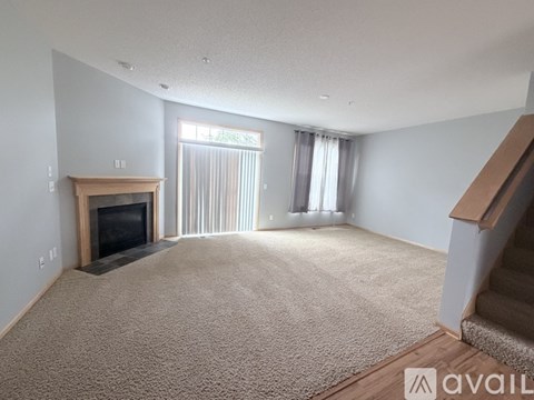 A living room with a carpeted floor and a fireplace.
