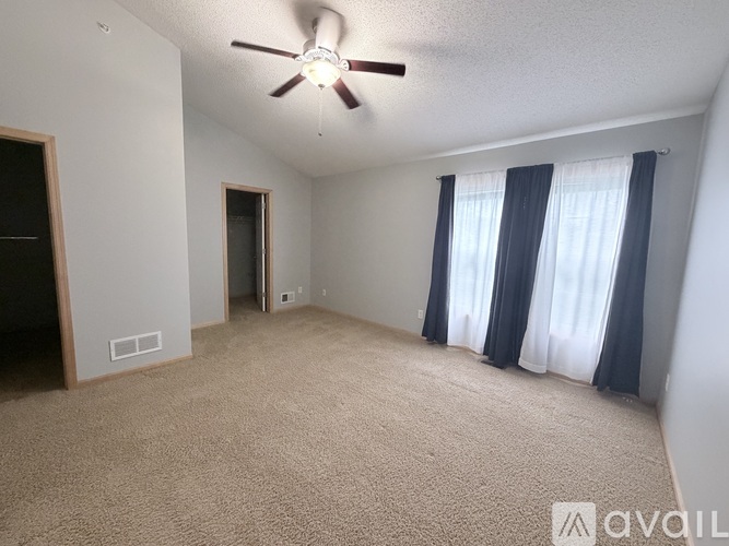A spacious room with a ceiling fan and carpeted floor.