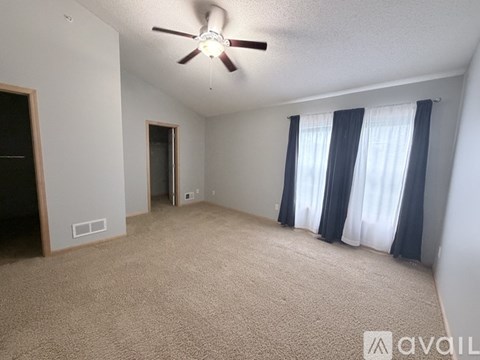 A spacious room with a ceiling fan and carpeted floor.