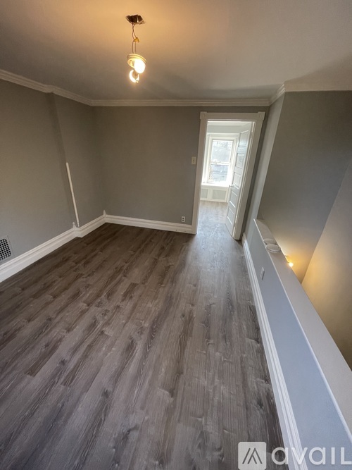 A room with wooden flooring and a window.