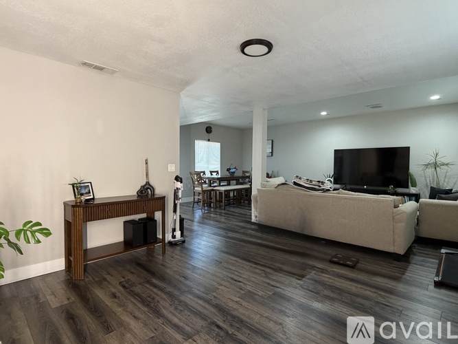 A living room with a television, couch, and a wooden table.