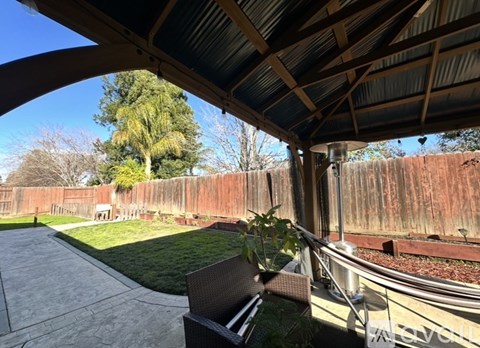A patio with a table and chairs is covered by a roof.