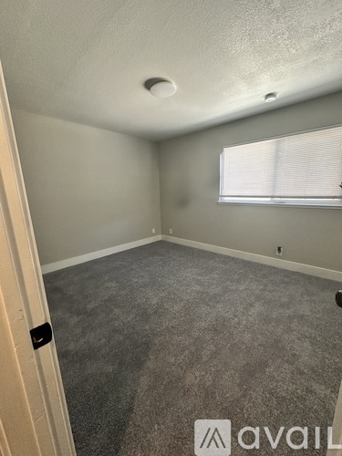 A room with a carpeted floor and a window with blinds.
