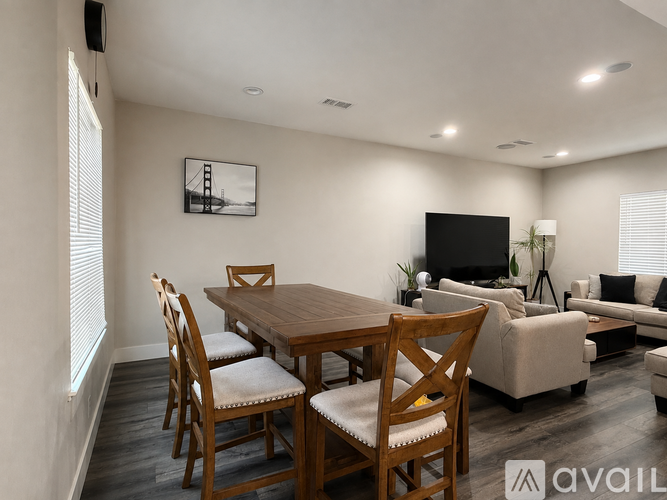 A living room with a wooden dining table and chairs, a couch, and a television.