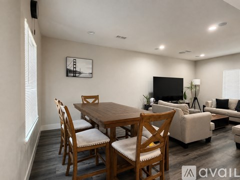A living room with a wooden dining table and chairs, a couch, and a television.