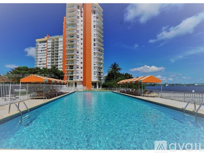 A large swimming pool in front of a tall building with orange umbrellas.
