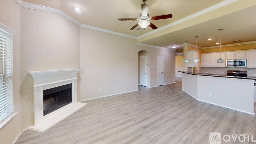 A spacious living room with a fireplace and a ceiling fan.