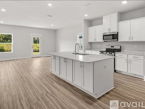 A kitchen with white cabinets and a wooden floor.