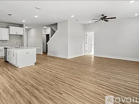 A spacious room with wooden flooring and a ceiling fan.