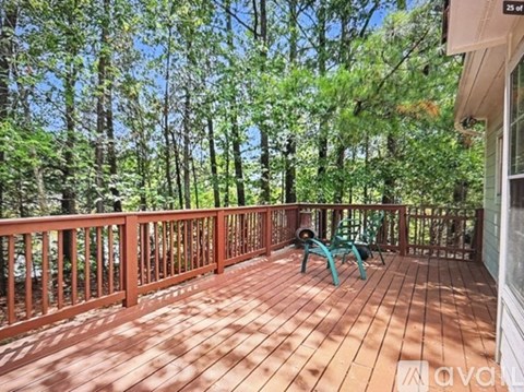 A wooden deck with a green chair and a railing.