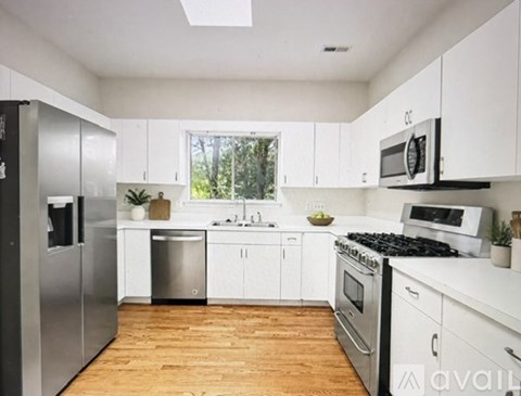 A kitchen with white cabinets and wooden floors.