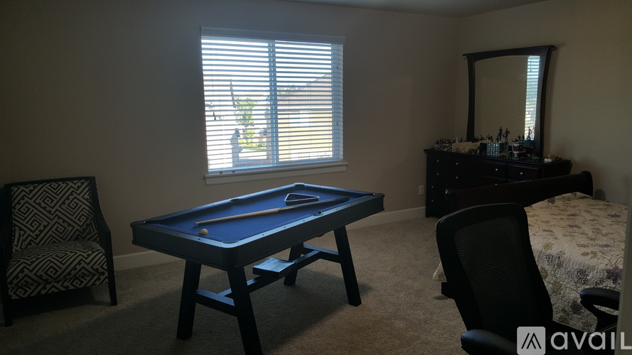 A pool table in a room with a chair and a mirror.