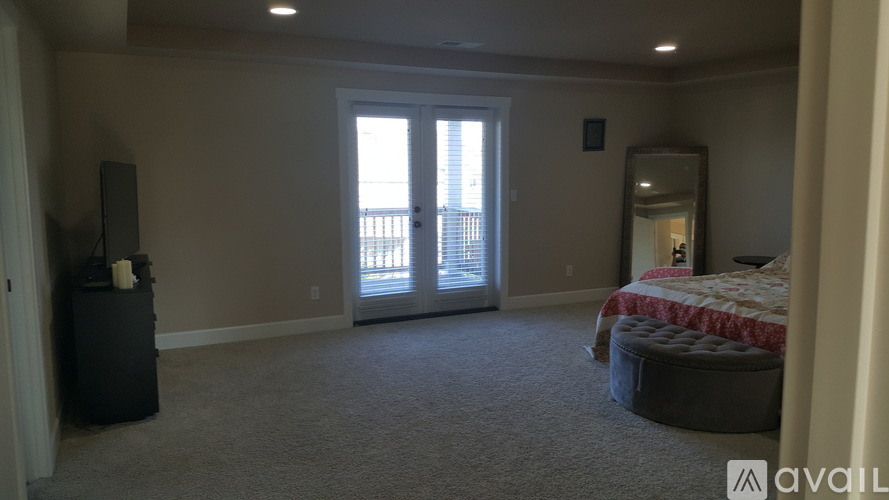 A bedroom with a bed, dresser, mirror, and sliding glass doors.