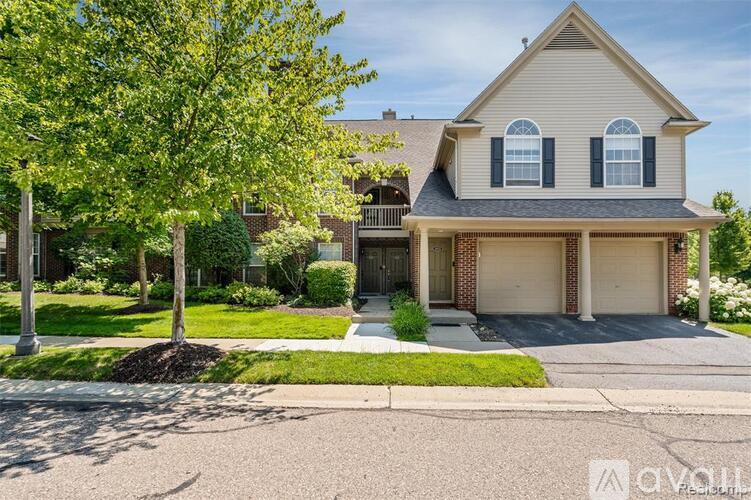 A two-story house with a garage and a tree in front.
