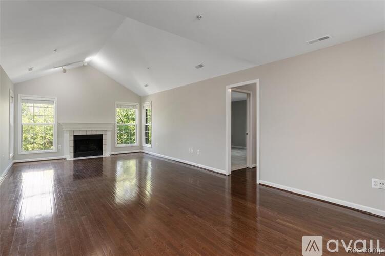 A spacious room with wooden floors and a fireplace.
