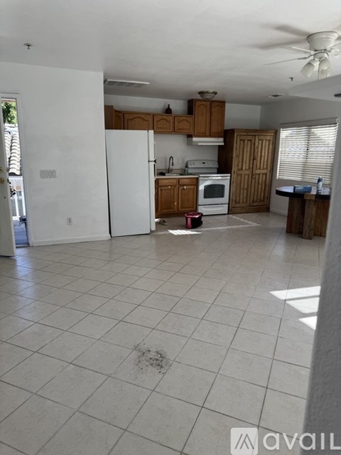 A kitchen with white tile flooring and wooden cabinets.