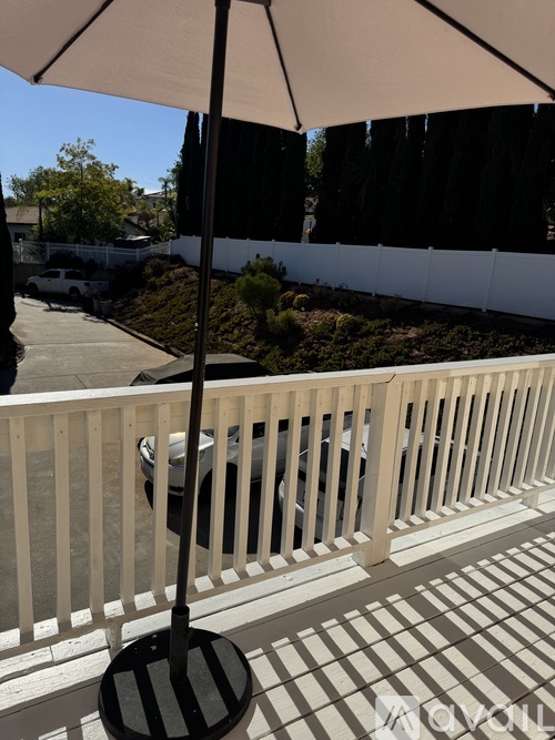 A patio with a white railing and a black and white striped umbrella pole.