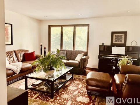 A living room with brown leather furniture and a glass coffee table.