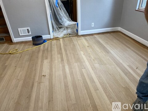 A room with wooden flooring and a yellow hose on the floor.