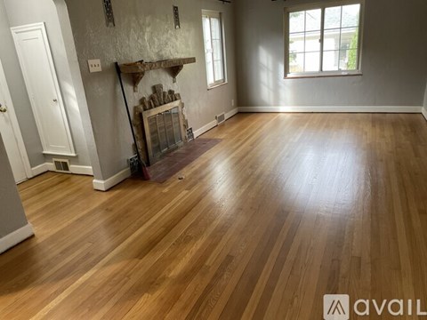 A room with wooden flooring and a fireplace.