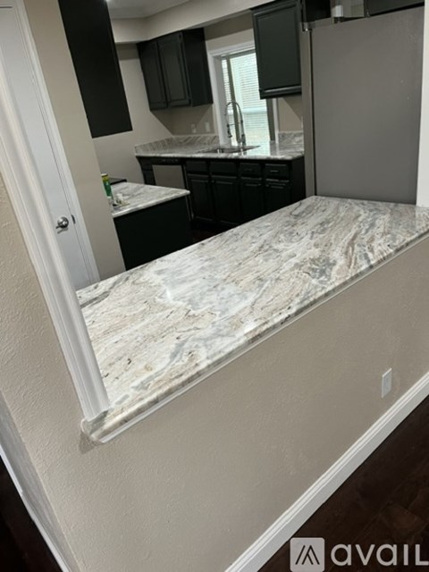A kitchen with black cabinets and a marble countertop.