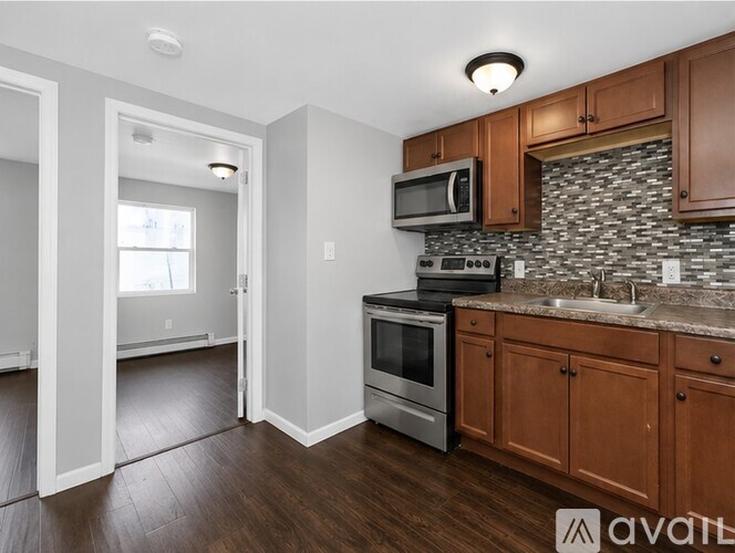 A kitchen with wooden cabinets and a stone backsplash is available.