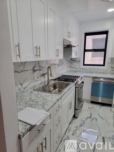 A kitchen with white cabinets and marble countertops.