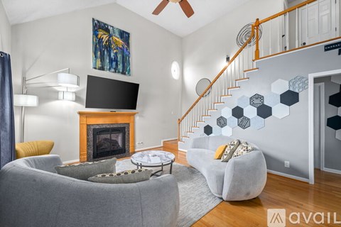 A living room with a grey couch, a fireplace, and a painting on the wall.