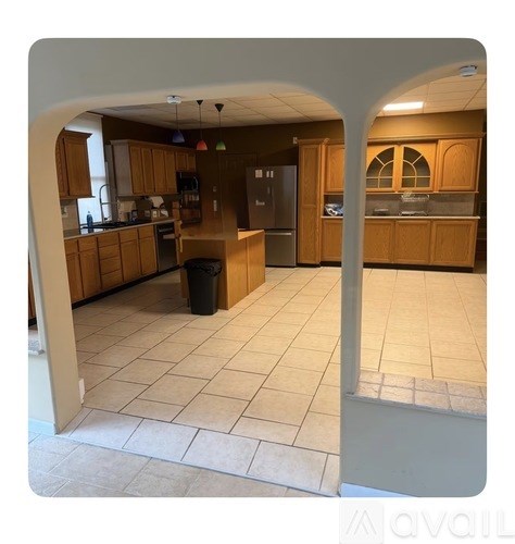 A kitchen with wooden cabinets and a black trash can.