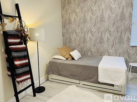 A bedroom with a bed, a chair, and a blanket on the floor.