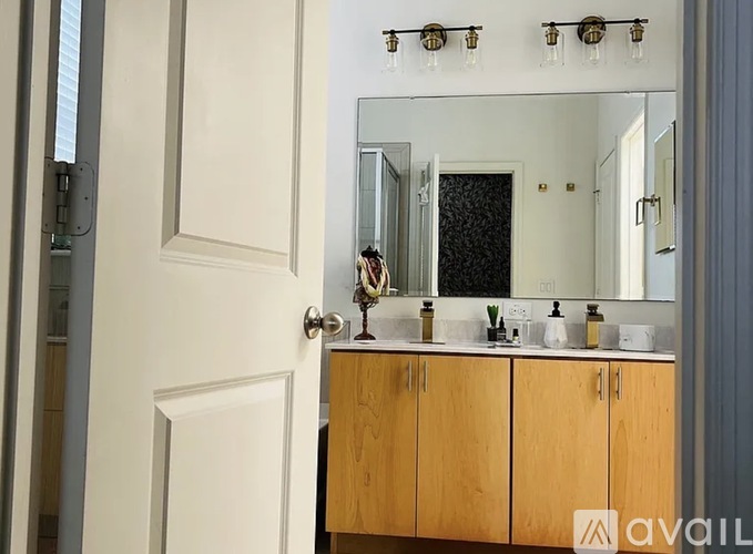 A bathroom with a white door, a mirror, and a wooden cabinet.