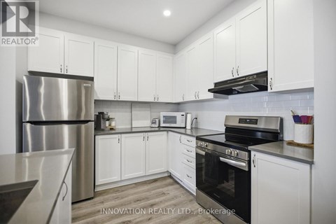 A modern kitchen with white cabinets and stainless steel appliances.