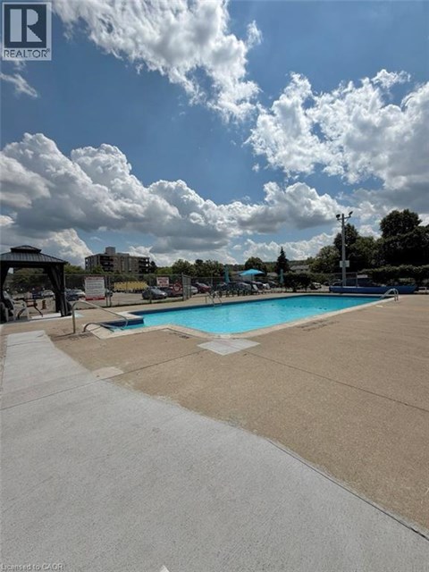 A swimming pool surrounded by a concrete deck and a cloudy sky.