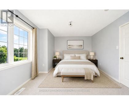 A bedroom with a large bed and a window overlooking a green area.