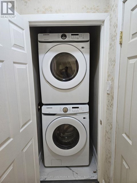 A stack of three white washing machines in a small laundry room.